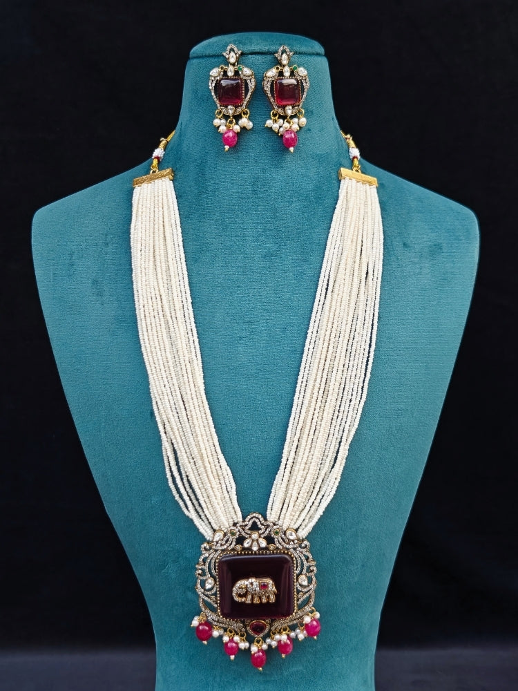 Close-up of an ornate traditional Ruby Pink (Mehendi Polish) Colored Stone jewellery set and earrings with American Diamond, Ruby Pink Colored Stones, Tumble Beads, Kundan and Pearls. Mehendi function outfit styled with a lightweight American Diamond necklace.