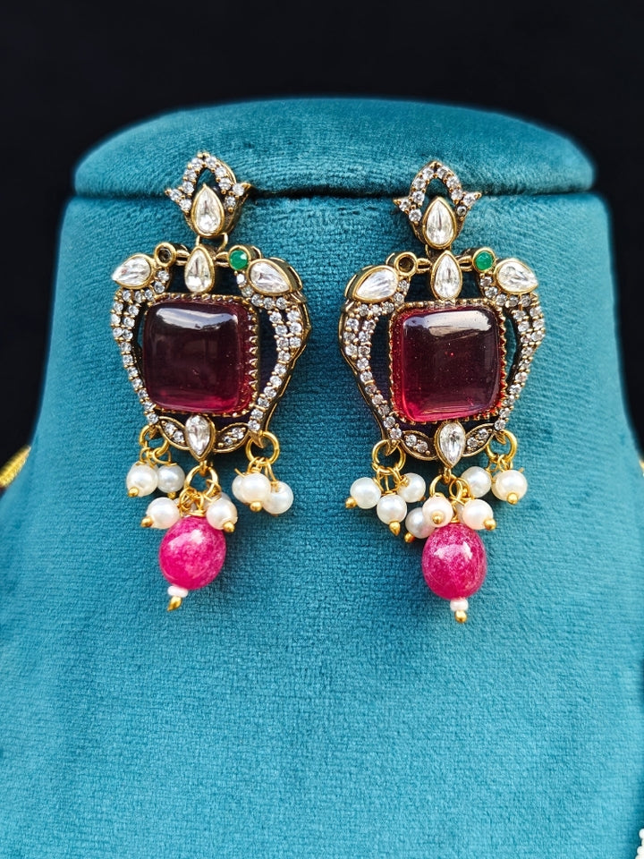 Close-up of an ornate traditional Ruby Pink (Mehendi Polish) Colored Stone jewellery set and earrings with American Diamond, Ruby Pink Colored Stones, Tumble Beads, Kundan and Pearls. Mehendi function outfit styled with a lightweight American Diamond necklace.