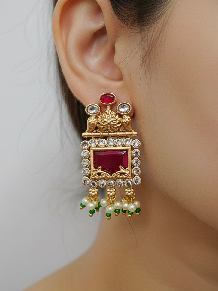 Close-up of a woman wearing an ornate traditional Red and Green Rajwadi gold Long jewellery set and earrings  with  Pearls, Beads, Ruby Red Colored Stones  and Bandhai Work. Mehendi ceremony look styled with a Rajwadi artificial jewelry set. Festive Diwali outfit enhanced with a Rajwadi artificial necklace.
