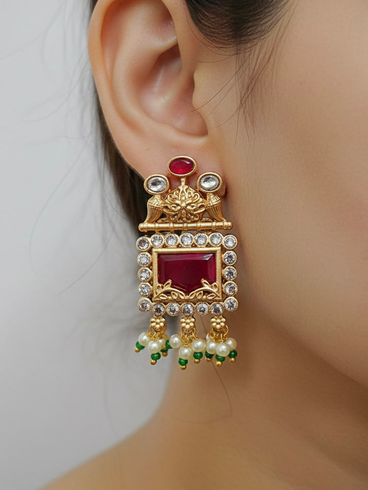 Close-up of a woman wearing an ornate traditional Red and Green Rajwadi gold Long jewellery set and earrings  with  Pearls, Beads, Ruby Red Colored Stones  and Bandhai Work. Mehendi ceremony look styled with a Rajwadi artificial jewelry set. Festive Diwali outfit enhanced with a Rajwadi artificial necklace.