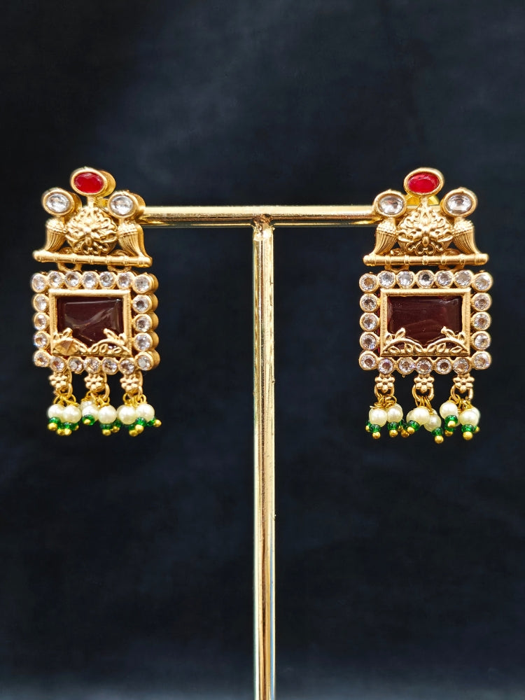 Close-up of a woman wearing an ornate traditional Red and Green Rajwadi gold Long jewellery set and earrings  with  Pearls, Beads, Ruby Red Colored Stones  and Bandhai Work. Mehendi ceremony look styled with a Rajwadi artificial jewelry set. Festive Diwali outfit enhanced with a Rajwadi artificial necklace.