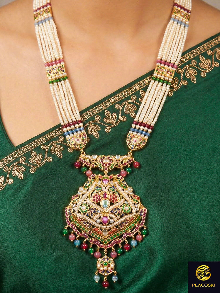 Close-up of a woman wearing an ornate traditional Navratan long jadau gold jewellery set and jadau earrings with pearls and gemstones. Saree look enhanced with a traditional Jadau artificial necklace. Close-up of a Jadau artificial necklace for wedding celebrations.