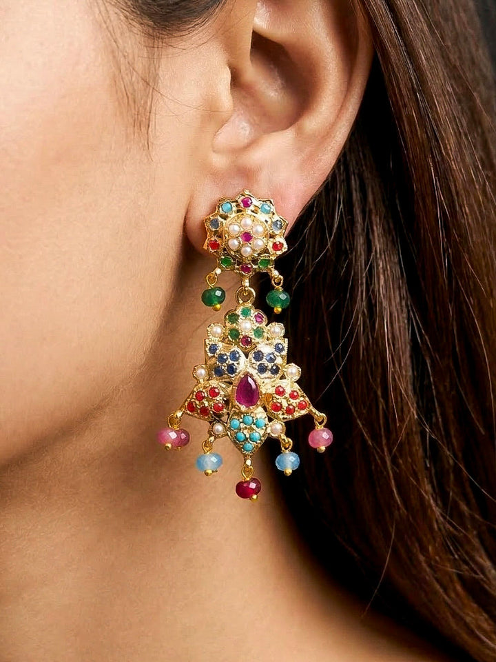 Close-up of a woman wearing an ornate traditional Navratan long jadau gold jewellery set and jadau earrings with pearls and gemstones. Woman wearing a royal Jadau necklace for festive events in India. Close-up of a Jadau artificial necklace for wedding celebrations.