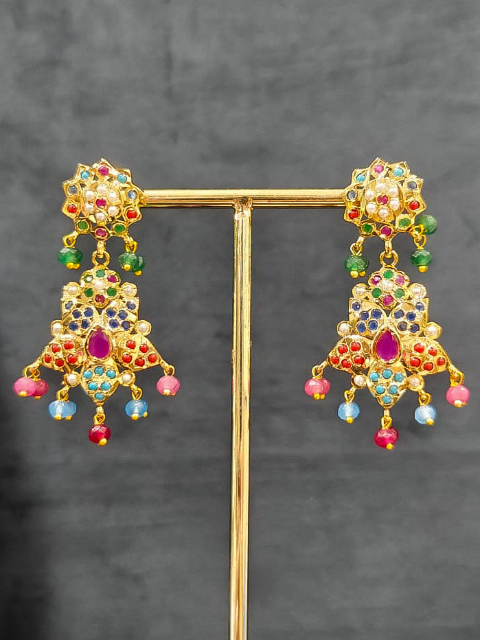 Close-up of an ornate traditional Navratan long jadau gold jewellery set and jadau earrings with pearls and gemstones. Elegant reception look featuring a luxury Jadau artificial jewelry set. Bridal styling inspiration with a premium Jadau imitation necklace.