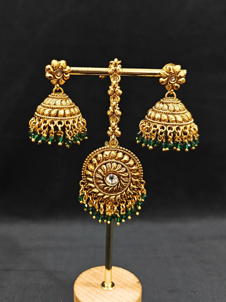 Close-up of an ornate traditional (Gold Polish) Choker jewellery set and earrings and maangtikka with Green Crystal Beads. Woman wearing a luxury artificial jewelry set styled for an Indian wedding celebration. Wedding celebration styling with a luxury artificial  jewelry design.