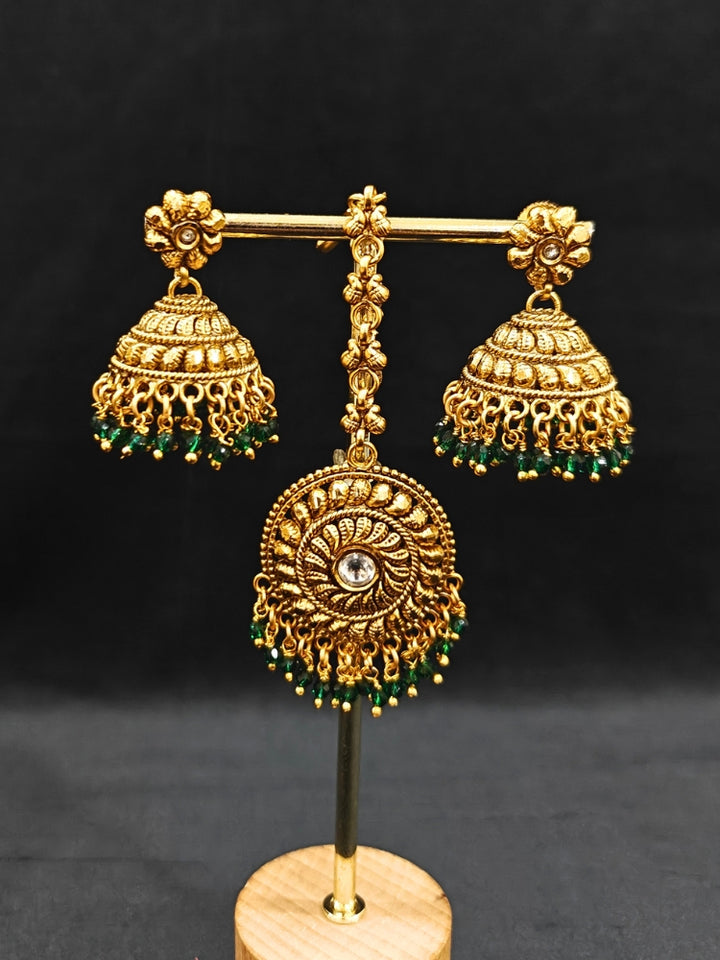 Close-up of an ornate traditional (Gold Polish) Choker jewellery set and earrings and maangtikka with Green Crystal Beads. Woman wearing a luxury artificial jewelry set styled for an Indian wedding celebration. Wedding celebration styling with a luxury artificial  jewelry design.