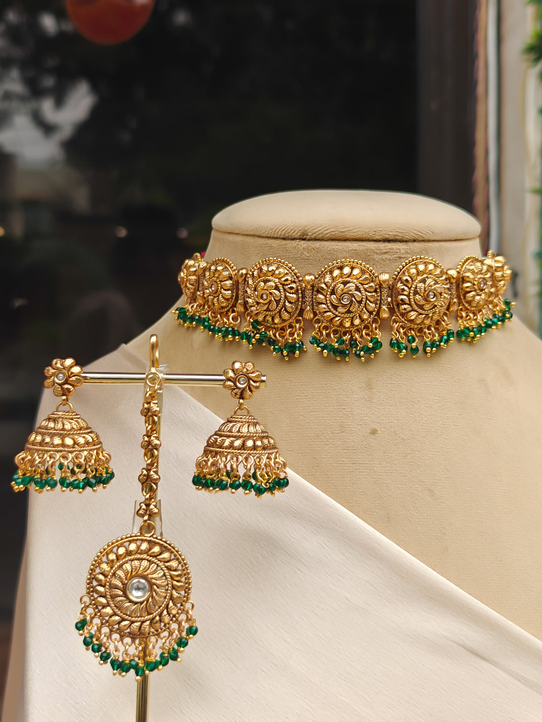 Close-up of an ornate traditional (Gold Polish) Choker jewellery set and earrings and maangtikka with Green Crystal Beads. Woman wearing a luxury artificial jewelry set styled for an Indian wedding celebration. Wedding celebration styling with a luxury artificial  jewelry design.