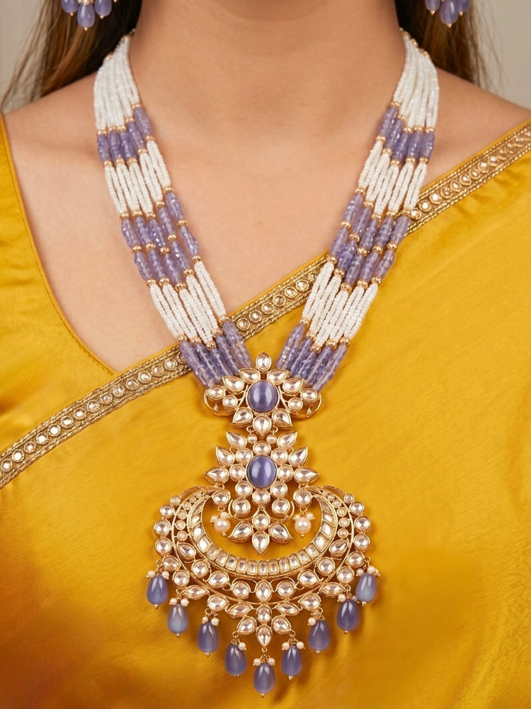 Close-up of a woman wearing an ornate traditional (Gold Polish) Lilac Long jewellery set and earrings with Polki,  Tumble Beads, Crystal Beads, Pearls and Colored Stone. Woman styling a premium Polki imitation necklace for wedding celebrations. Wedding guest outfit styled with an elegant Polki necklace set.