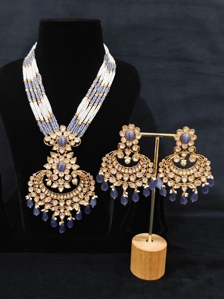 Close-up of an ornate traditional (Gold Polish) Lilac Long jewellery set and earrings with Polki,  Tumble Beads, Crystal Beads, Pearls and Colored Stone. Woman styling a premium Polki imitation necklace for wedding celebrations. Wedding guest outfit styled with an elegant Polki necklace set.