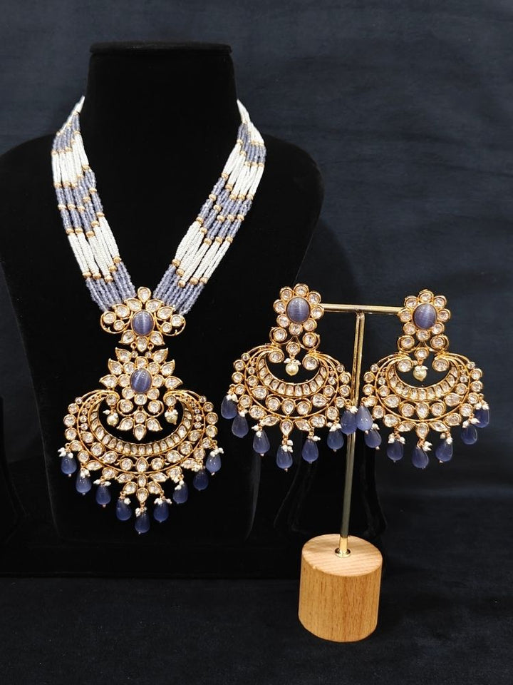 Close-up of an ornate traditional (Gold Polish) Lilac Long jewellery set and earrings with Polki,  Tumble Beads, Crystal Beads, Pearls and Colored Stone. Woman styling a premium Polki imitation necklace for wedding celebrations. Wedding guest outfit styled with an elegant Polki necklace set.
