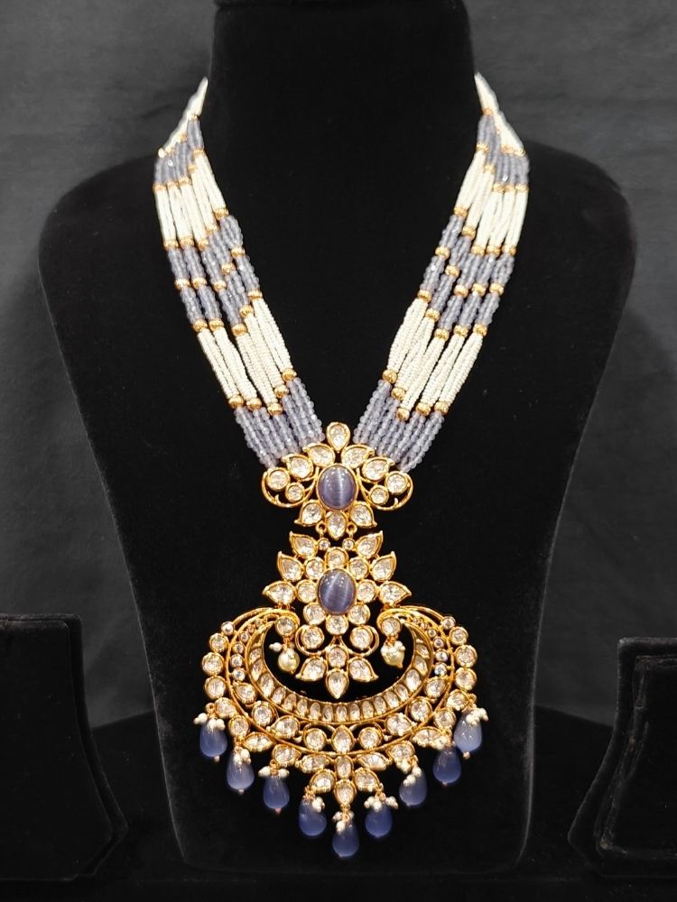 Close-up of an ornate traditional (Gold Polish) Lilac Long jewellery set and earrings with Polki,  Tumble Beads, Crystal Beads, Pearls and Colored Stone. Woman styling a premium Polki imitation necklace for wedding celebrations. Wedding guest outfit styled with an elegant Polki necklace set.