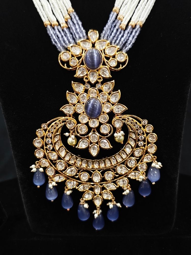 Close-up of an ornate traditional (Gold Polish) Lilac Long jewellery set and earrings with Polki,  Tumble Beads, Crystal Beads, Pearls and Colored Stone. Woman styling a premium Polki imitation necklace for wedding celebrations. Wedding guest outfit styled with an elegant Polki necklace set.