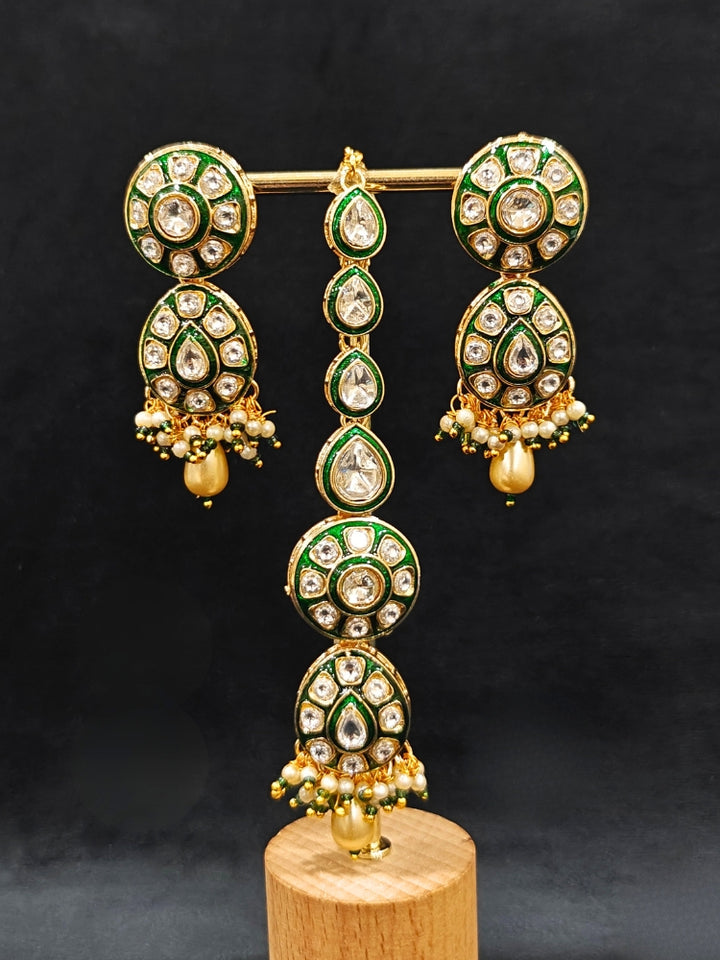 Close-up of an ornate traditional Green Jewelry Set, Earrings and Mangtikka with Kundan. Bride wearing a traditional Kundan artificial necklace set for her wedding ceremony. Woman wearing trending Kundan artificial jewelry for wedding season in India.