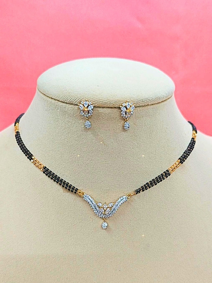 Supriya Mangalsutra—a gold necklace with black mangalsutra beads and matching earrings, pendant featuring sparkling American Diamonds—set against a cream dummy, perfect for your wedding ceremony dress. Diamond mangalsutra. Modern mangalsutra. 