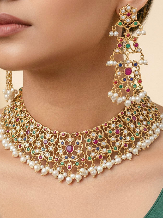Close-up of a woman wearing an ornate traditional collar Navratan jadau gold jewellery set and jadau earrings with pearls and Navratan gemstones. Woman wearing a premium Jadau artificial jewelry set for reception night. Bridal styling inspiration with a premium Jadau imitation necklace.