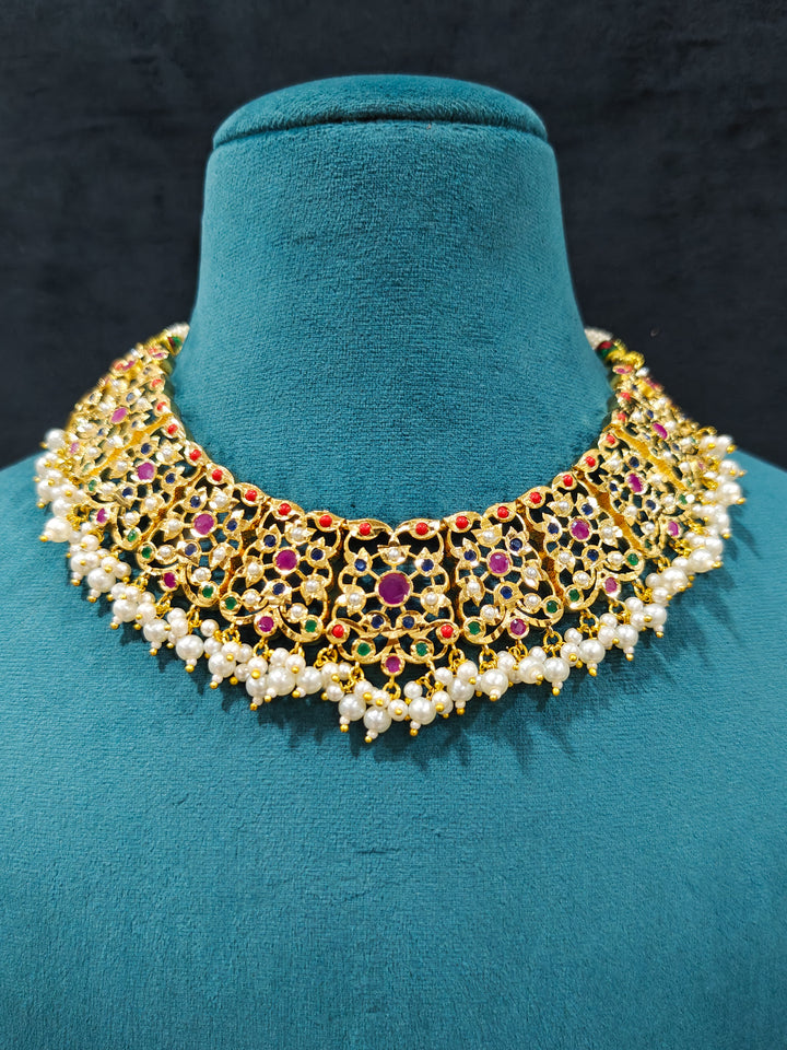 Close-up of an ornate traditional collar Navratan jadau gold jewellery set and jadau earrings with pearls and Navratan gemstones. Close-up of a Jadau artificial necklace for wedding celebrations. Close-up of intricate Jadau detailing in artificial bridal jewelry.