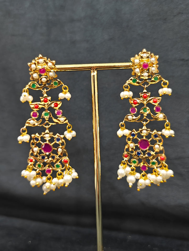 Close-up of an ornate traditional collar Navratan jadau gold jewellery set and jadau earrings with pearls and Navratan gemstones. Close-up of a Jadau artificial necklace for wedding celebrations. Close-up of intricate Jadau detailing in artificial bridal jewelry.