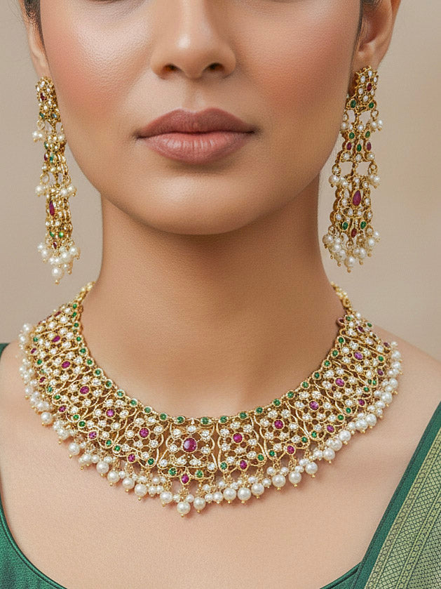 Close-up of a woman wearing an ornate traditional collar Ruby Pink and Green  jadau gold jewellery set and jadau earrings with pearls and Navratan gemstones. Bride wearing a traditional Jadau artificial necklace set for her wedding ceremony. Festive celebration look featuring a Jadau artificial necklace.