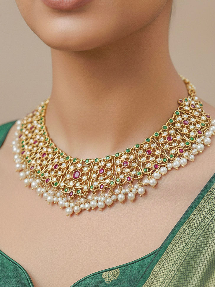 Close-up of a woman wearing an ornate traditional collar Ruby Pink and Green  jadau gold jewellery set and jadau earrings with pearls and Navratan gemstones. Bride wearing a traditional Jadau artificial necklace set for her wedding ceremony. Festive celebration look featuring a Jadau artificial necklace.