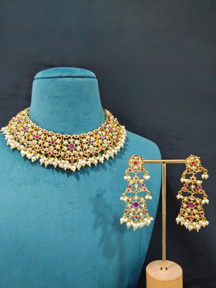 Close-up of an ornate traditional Ruby Pink jadau gold jewellery set and jadau earrings with pearls and stones. Elegant reception look featuring a luxury Jadau artificial jewelry set. Perfect Jadau necklace set for weddings and festivals. 