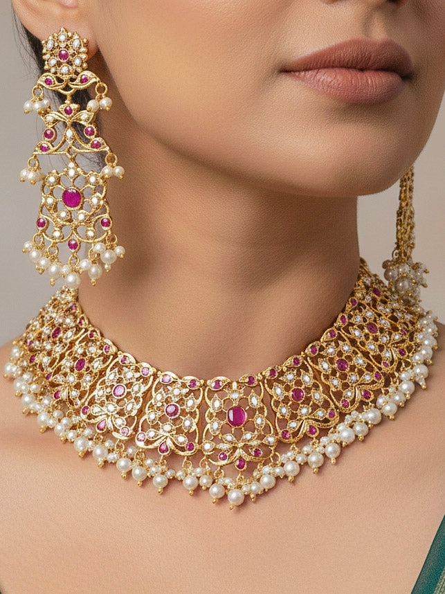 Close-up of a woman wearing an ornate traditional Ruby Pink jadau gold jewellery set and jadau earrings with pearls and stones. Perfect Jadau necklace set for weddings and festivals. Woman pairing a traditional Jadau necklace with a silk saree.