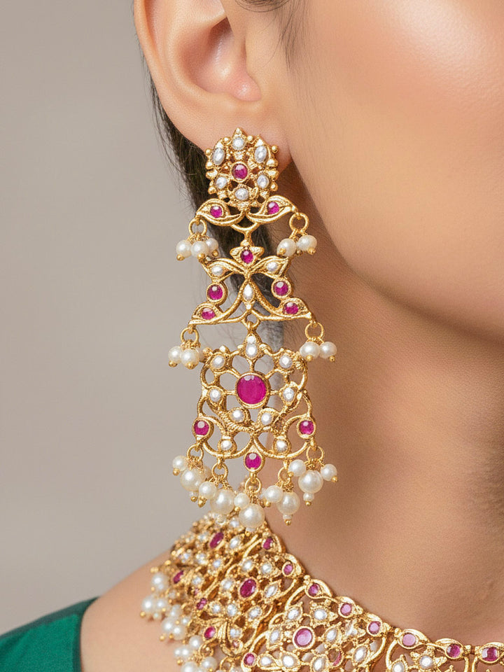 Close-up of a woman wearing an ornate traditional Ruby Pink jadau gold jewellery set and jadau earrings with pearls and stones. Perfect Jadau necklace set for weddings and festivals. Woman pairing a traditional Jadau necklace with a silk saree.