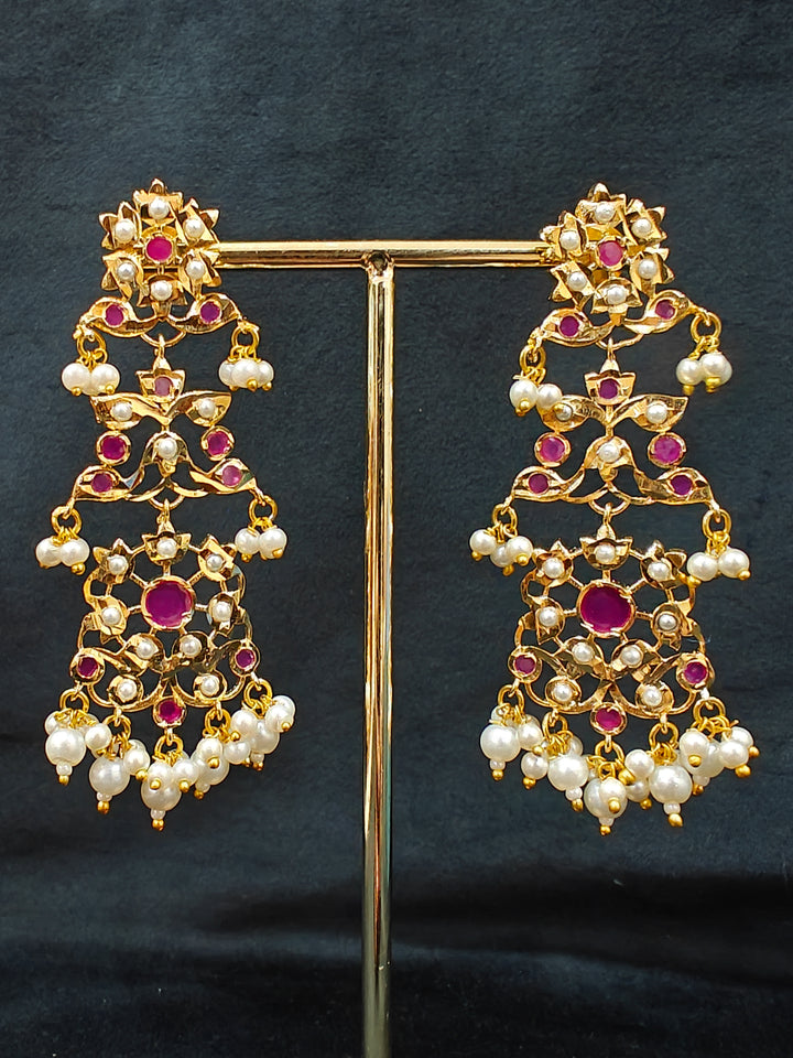 Close-up of an ornate traditional Ruby Pink jadau gold jewellery set and jadau earrings with pearls and stones. Elegant reception look featuring a luxury Jadau artificial jewelry set. Perfect Jadau necklace set for weddings and festivals. 