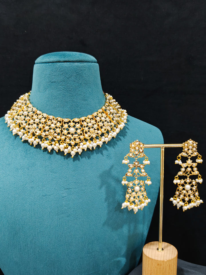 Close-up of a gold Indian traditional White jadau jewellery with pearls and jadau stones, and matching jadau earrings. This authentic jadau jewelry set can we worn as jadau necklace set for weddings. Close-up of high-quality Jadau artificial necklace craftsmanship. Festive celebration look featuring a Jadau artificial necklace.