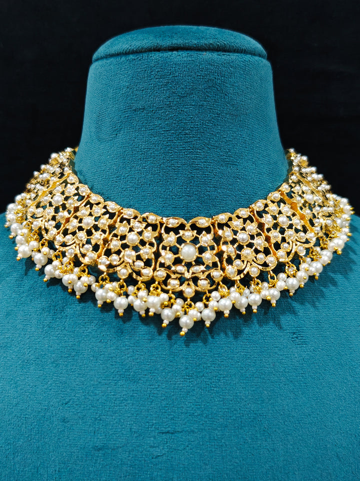Close-up of a gold Indian traditional White jadau jewellery with pearls and jadau stones, and matching jadau earrings. This authentic jadau jewelry set can we worn as jadau necklace set for weddings. Close-up of high-quality Jadau artificial necklace craftsmanship. Festive celebration look featuring a Jadau artificial necklace.