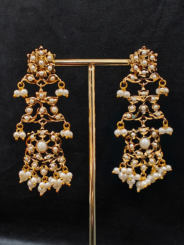Close-up of a gold Indian traditional White jadau jewellery with pearls and jadau stones, and matching jadau earrings. This authentic jadau jewelry set can we worn as jadau necklace set for weddings. Close-up of high-quality Jadau artificial necklace craftsmanship. Festive celebration look featuring a Jadau artificial necklace.