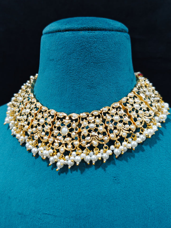 Close-up of a gold Indian traditional White jadau jewellery with pearls and jadau stones, and matching jadau earrings. This authentic jadau jewelry set can we worn as jadau necklace set for weddings. Close-up of high-quality Jadau artificial necklace craftsmanship. Festive celebration look featuring a Jadau artificial necklace.