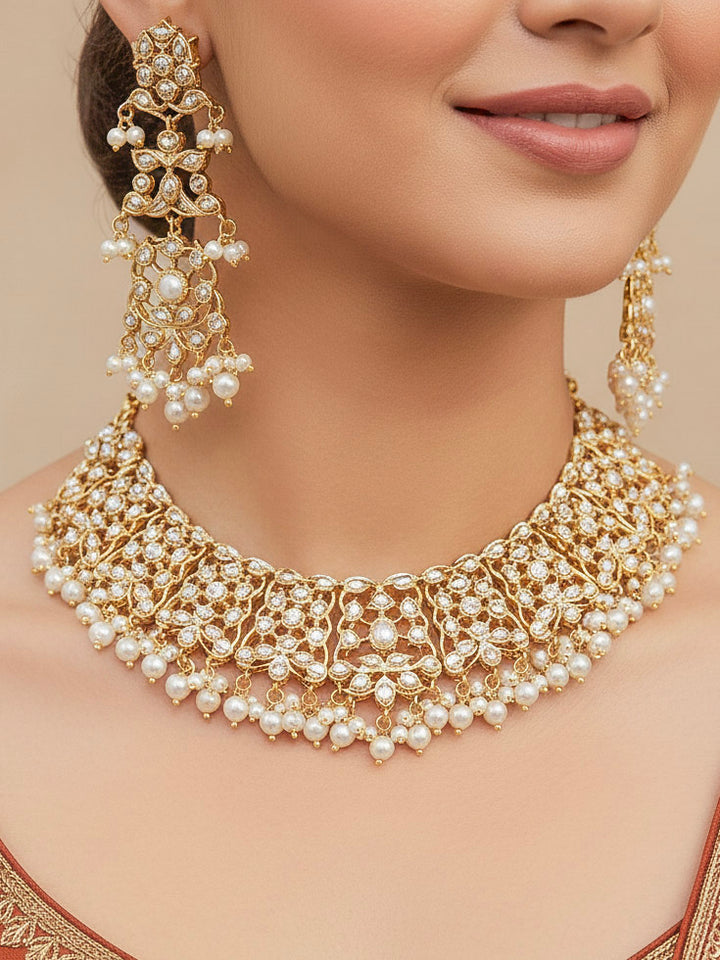 Close-up of a woman wearing an ornate traditional jadau gold jewellery set and jadau earrings with pearls and stones. Perfect Jadau necklace set for weddings and festivals. 