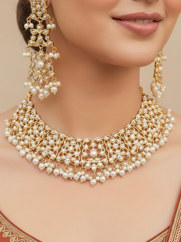 Close-up of a woman wearing a gold Indian traditional jadau jewellery with pearls and jadau stones, and matching jadau earrings. This authentic jadau jewelry set can we worn as jadau necklace set for weddings. 