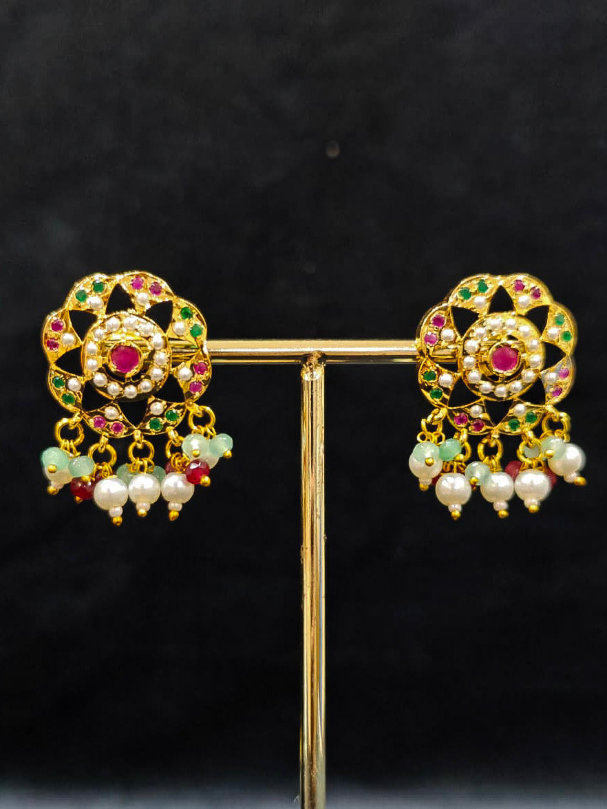 Close-up of an ornate traditional Choker jadau gold jewellery set and  jadau earrings with Pearl, Beads, and Pink & Green Colored Stone. Wedding guest styling a statement Jadau artificial necklace. A royal Jadau necklace for festive events in India.