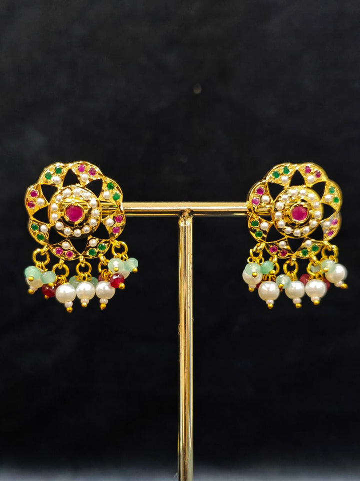 Close-up of an ornate traditional Choker jadau gold jewellery set and  jadau earrings with Pearl, Beads, and Pink & Green Colored Stone. Wedding guest styling a statement Jadau artificial necklace. A royal Jadau necklace for festive events in India.