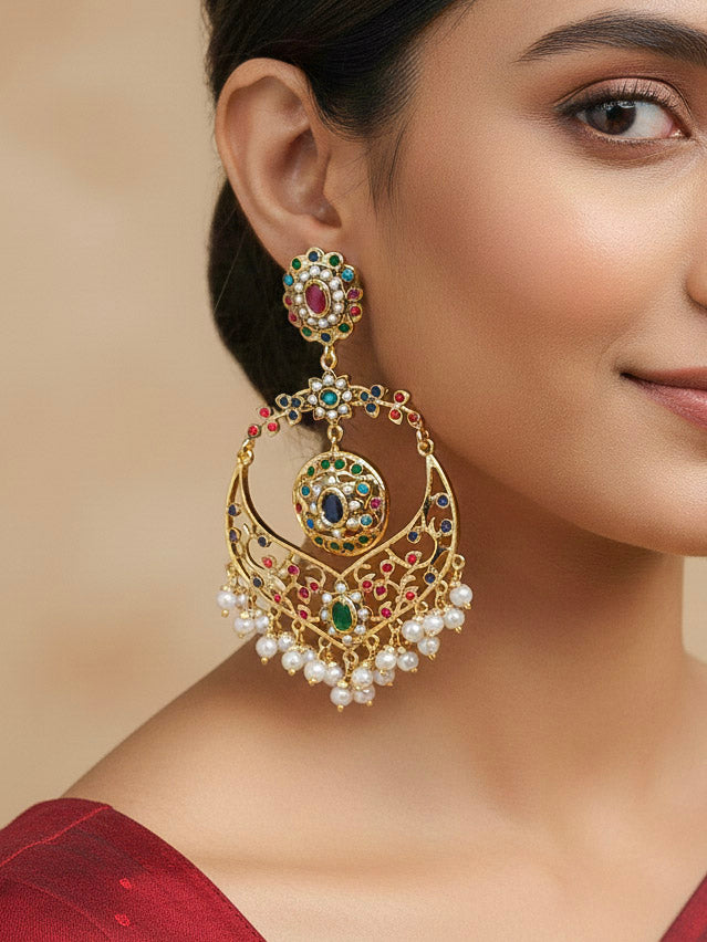 Close-up of a woman wearing an ornate traditional Navratan jadau gold earrings with pearls and Color Stone. Woman wearing statement artificial Jadau earrings for a wedding guest look in India. Perfect Jadau Earrings set for weddings and festivals.