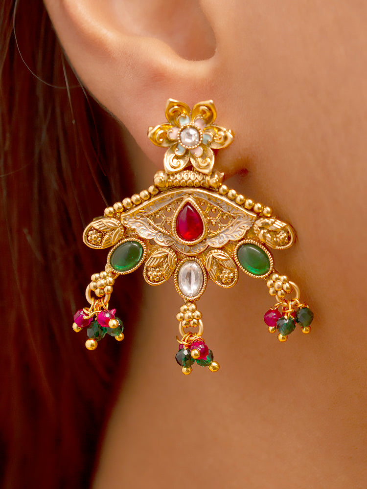 A woman smiles softly wearing the Svarlina Green & Pink Necklace Set, featuring a Kundan necklace with green and red crystal stones, matching earrings, and a gold-embroidered pink traditional outfit—ideal elegant party wear jewelry.