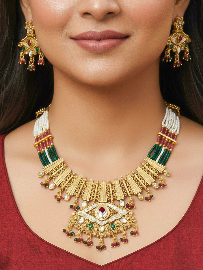 Close-up of a woman wearing an ornate traditional (Gold Polish) Pink & Green Collar jewellery set and earrings with Crystal Beads, Meenakari, Pearl and Colored Stone. Bride wearing a high-quality artificial Meenakari jewelry set for wedding rituals. Woman wearing lightweight artificial Meenakari jewelry for long wedding functions.