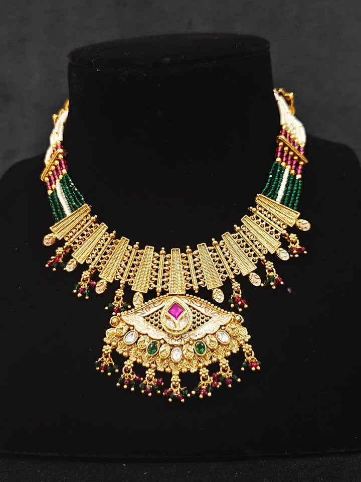 Close-up of a woman wearing an ornate traditional (Gold Polish) Pink & Green Collar jewellery set and earrings with Crystal Beads, Meenakari, Pearl and Colored Stone. Bride wearing a high-quality artificial Meenakari jewelry set for wedding rituals. Woman wearing lightweight artificial Meenakari jewelry for long wedding functions.