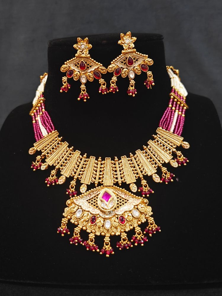 Close-up of an ornate traditional (Gold Polish) Pink Collar jewellery set and earrings with Crystal Beads, Meenakari, Pearl and Colored Stone. Bride wearing a high-quality artificial Meenakari jewelry set for wedding rituals. Woman wearing lightweight artificial Meenakari jewelry for long wedding functions.