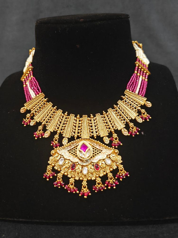 Close-up of an ornate traditional (Gold Polish) Pink Collar jewellery set and earrings with Crystal Beads, Meenakari, Pearl and Colored Stone. Bride wearing a high-quality artificial Meenakari jewelry set for wedding rituals. Woman wearing lightweight artificial Meenakari jewelry for long wedding functions.