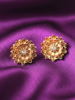 The Tanisha Gold stud Earrings, crafted from brass with gold floral designs featuring intricate petals and a central gemstone. Indo-western dress styled with lightweight artificial American Diamond Studs earrings. Festive Diwali look styled with premium artificial American Diamond Studs earrings.