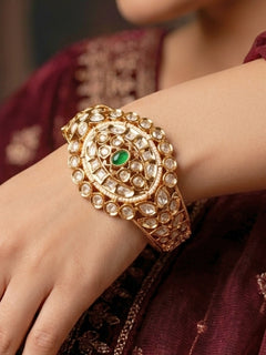 Close-up of a woman wearing an ornate traditional (Gold Polish) Green Bracelet with Polki, Green Colored Stone and Pearl. Wedding guest wearing a minimal artificial Polki bracelet. Close-up of a high-quality imitation Polki bracelet for festive wear.