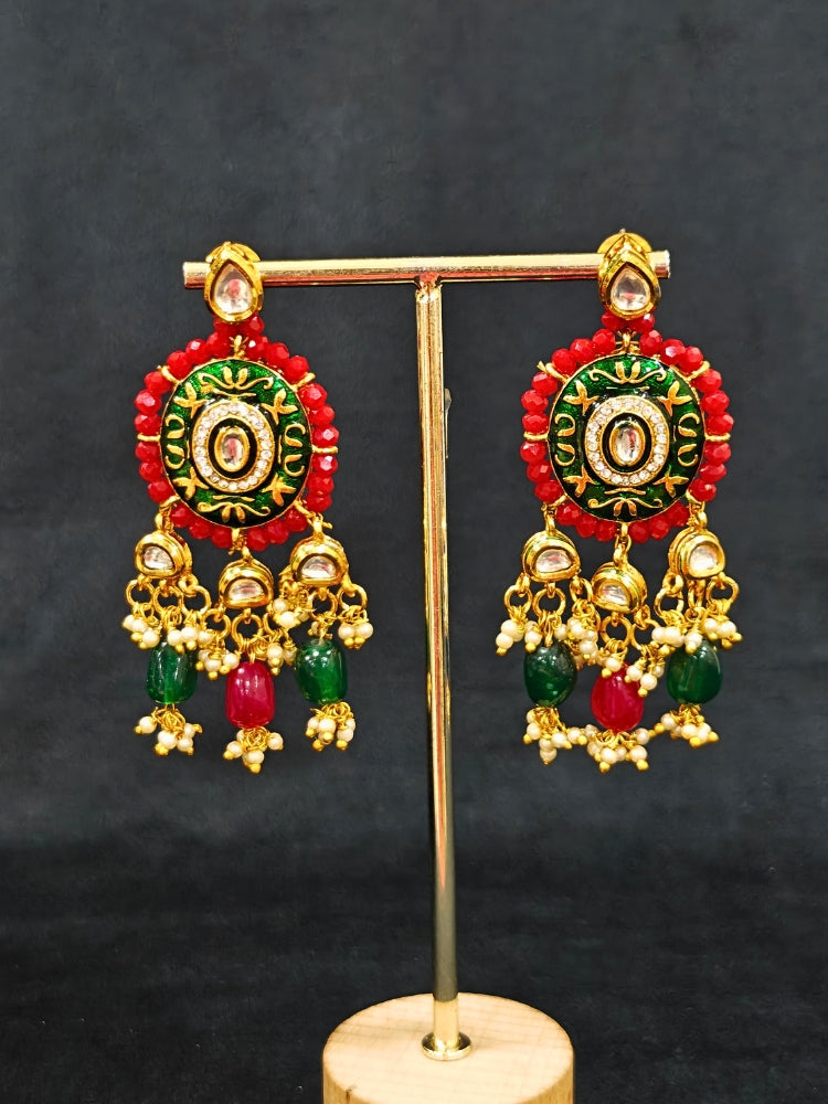 Close-up of an ornate traditional Red and Green Meenakari gold Choker jewellery set and earrings with Kundan, Meenakari Work, Red & Green Crystal Beads, Pearls and Red & Green Tumble Stone. Saree look completed with an elegant Meenakari artificial jewelry piece. Perfect Meenakari necklace set for weddings and festivals.
