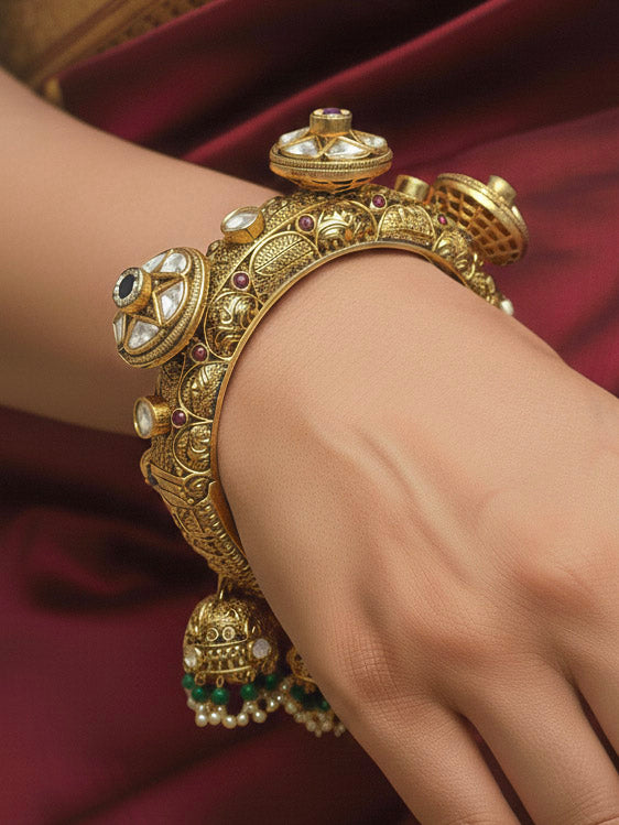 Close-up of a woman wearing an ornate traditional (Gold Polish) Bracelet with Polki, Pearls and Colored Stone. Woman styling a vintage heritage artificial Heritage Bracelet for a reception party. Woman wearing a heritage-style artificial Heritage Bracelet for long wedding functions.