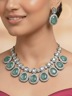 Close-up of a woman wearing an ornate Indo-western American Diamond Teel Green Collar jewellery set and earrings with American Diamonds and Monalisa Stones. Woman styling a statement American diamond necklace with an off-shoulder gown for a reception. Close-up of a luxury American Diamond imitation necklace styled.