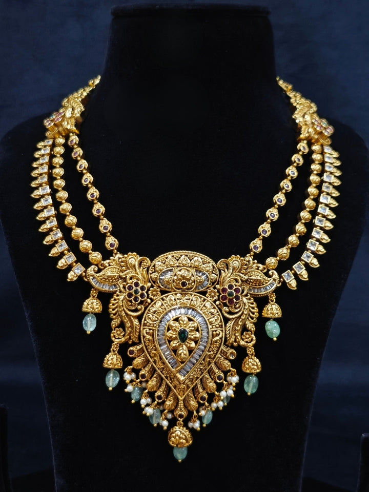 Close-up of an ornate traditional (Gold Polish) Collar jewellery set and earrings with American Diamond, Tumble Beads and Polki. Woman wearing a luxury artificial American Diamond jewelry set styled for an Indian wedding celebration. Traditional Indian bridal look featuring a premium imitation American Diamond jewelry set.