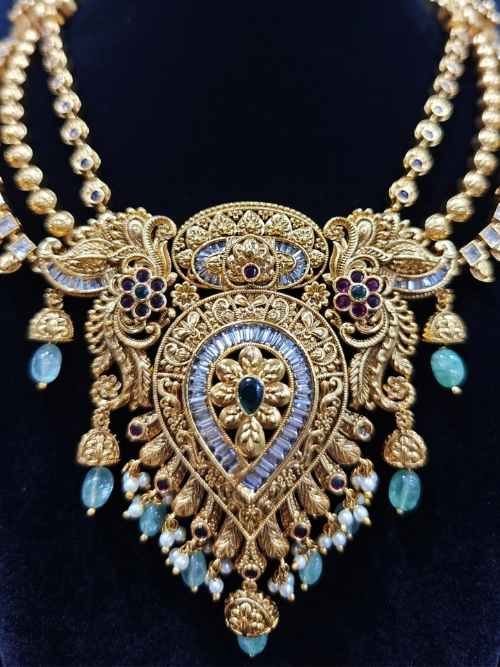 Close-up of an ornate traditional (Gold Polish) Collar jewellery set and earrings with American Diamond, Tumble Beads and Polki. Woman wearing a luxury artificial American Diamond jewelry set styled for an Indian wedding celebration. Traditional Indian bridal look featuring a premium imitation American Diamond jewelry set.