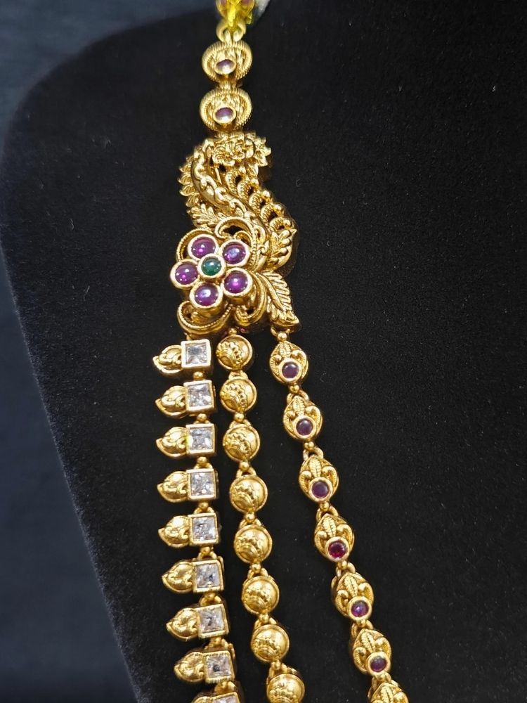 Close-up of an ornate traditional (Gold Polish) Collar jewellery set and earrings with American Diamond, Tumble Beads and Polki. Woman wearing a luxury artificial American Diamond jewelry set styled for an Indian wedding celebration. Traditional Indian bridal look featuring a premium imitation American Diamond jewelry set.