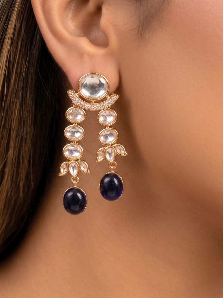Close-up of a woman wearing an ornate traditional (Gold Polish) Navy Blue Layered jewellery set and earrings with Polki and Navy Blue Colored Stones. Wedding guest wearing a statement Polki artificial necklace for a reception party. Woman styling a premium Polki imitation necklace for wedding celebrations.